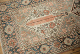Distressed vintage Bakhtiari runner showing tangerine floral and geometric medallion details.