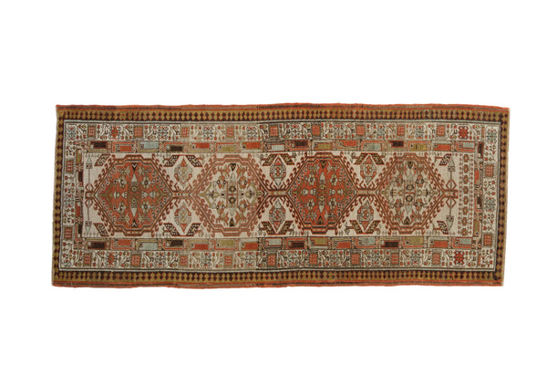 Distressed vintage Serab runner with geometric medallions in ivory, madder red, and pale blue.
