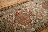 Close-up of distressed Serab runner, geometric border and faded red, green, ivory field.