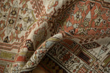 Distressed Serab runner with worn texture and geometric patterns in ivory, red, and green.