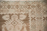 Distressed Hamadan rug detail, showing geometric border with pale brown, ivory, and seafoam green.