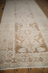 Geometric relief border with time-softened tones on a distressed Hamadan runner.