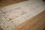 Distressed vintage Hamadan runner close-up showing geometric border and primitive plant motifs with soft wear.