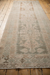 Distressed vintage Hamadan runner's geometric border with pale beige, seafoam, and secured end.