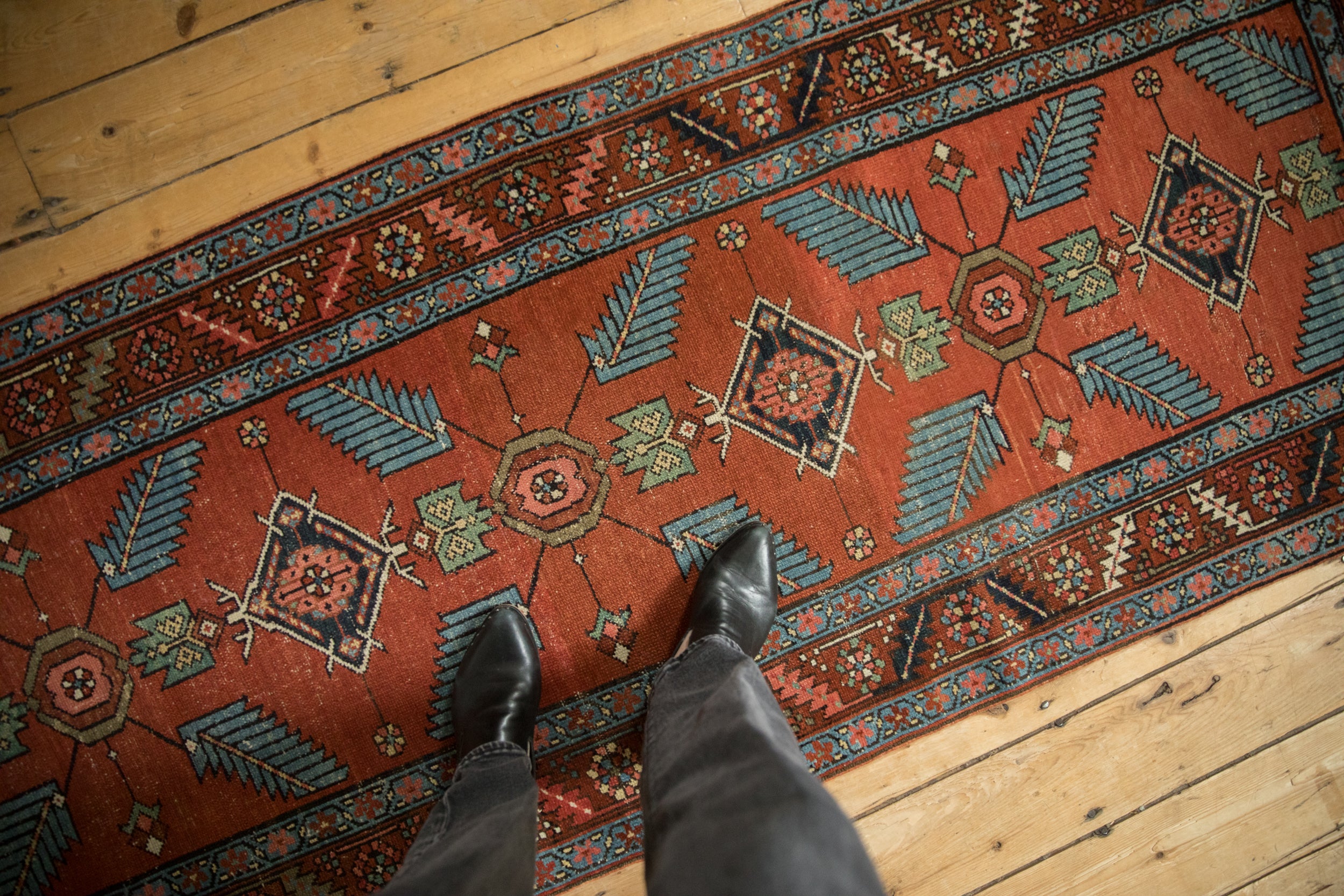 Antique Northwest Persian runner featuring sprawling finned leaves, red field, and serrated border.