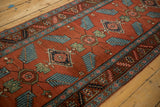 Antique Northwest Persian runner: rust field, sprawling blue finned leaves, ornate floral border.
