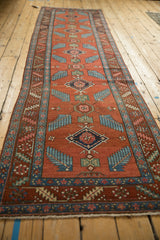 Antique Persian runner showing rust red field, sky blue finned leaves, and floral motifs.