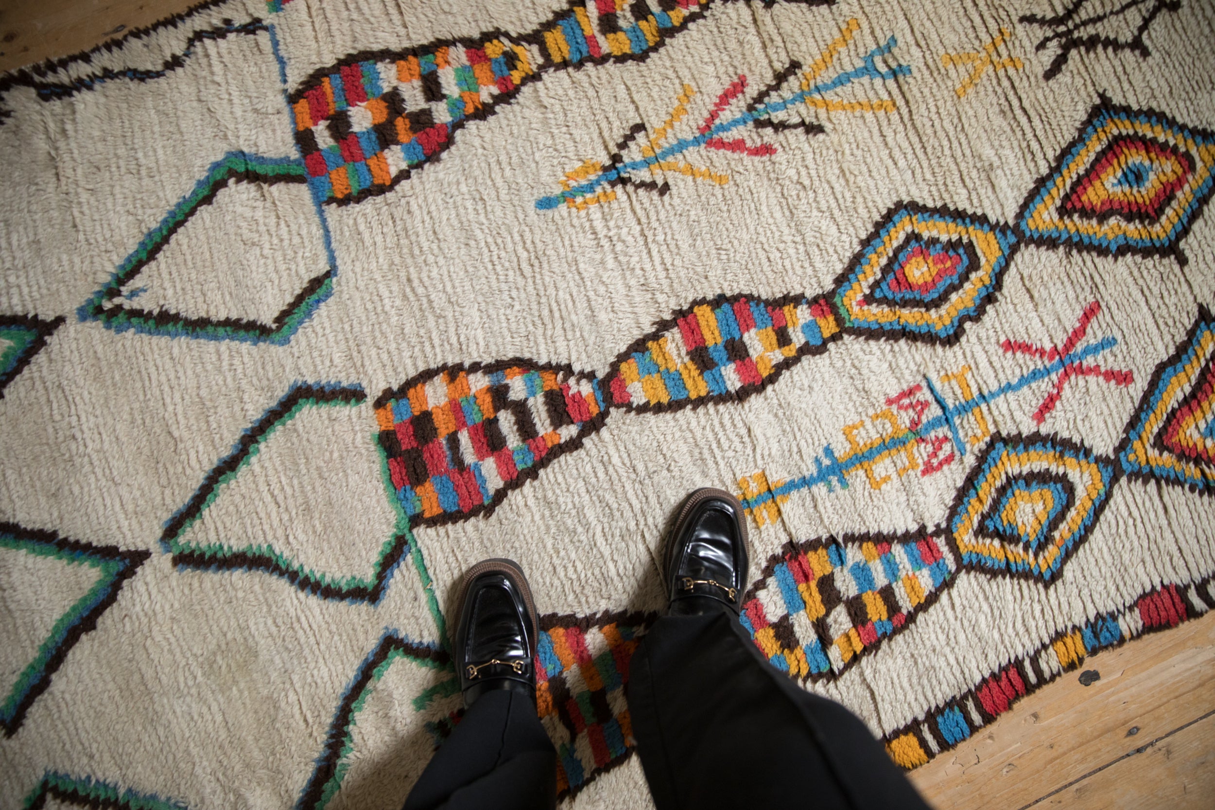 Vintage Moroccan rug detail: textured ivory pile, abstract diamonds, and colorful concentric fills.
