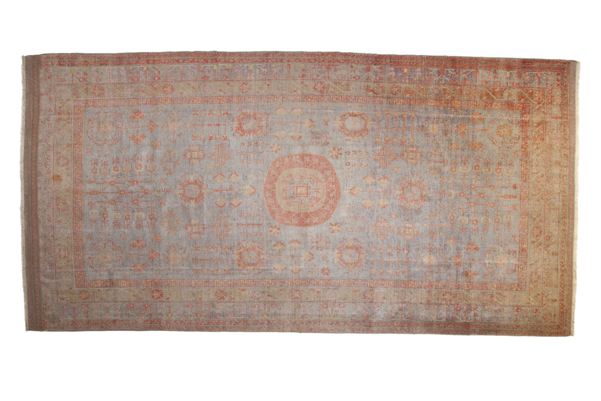 Antique Khotan carpet with time-softened blue field, roundel medallion, and pale rust patterns.