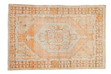 Distressed vintage Oushak rug with faded orange floral medallion and coffee brown geometric borders.