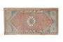 Distressed vintage Oushak rug mat with a serrated medallion in faded dusty red, blue, and tangerine.