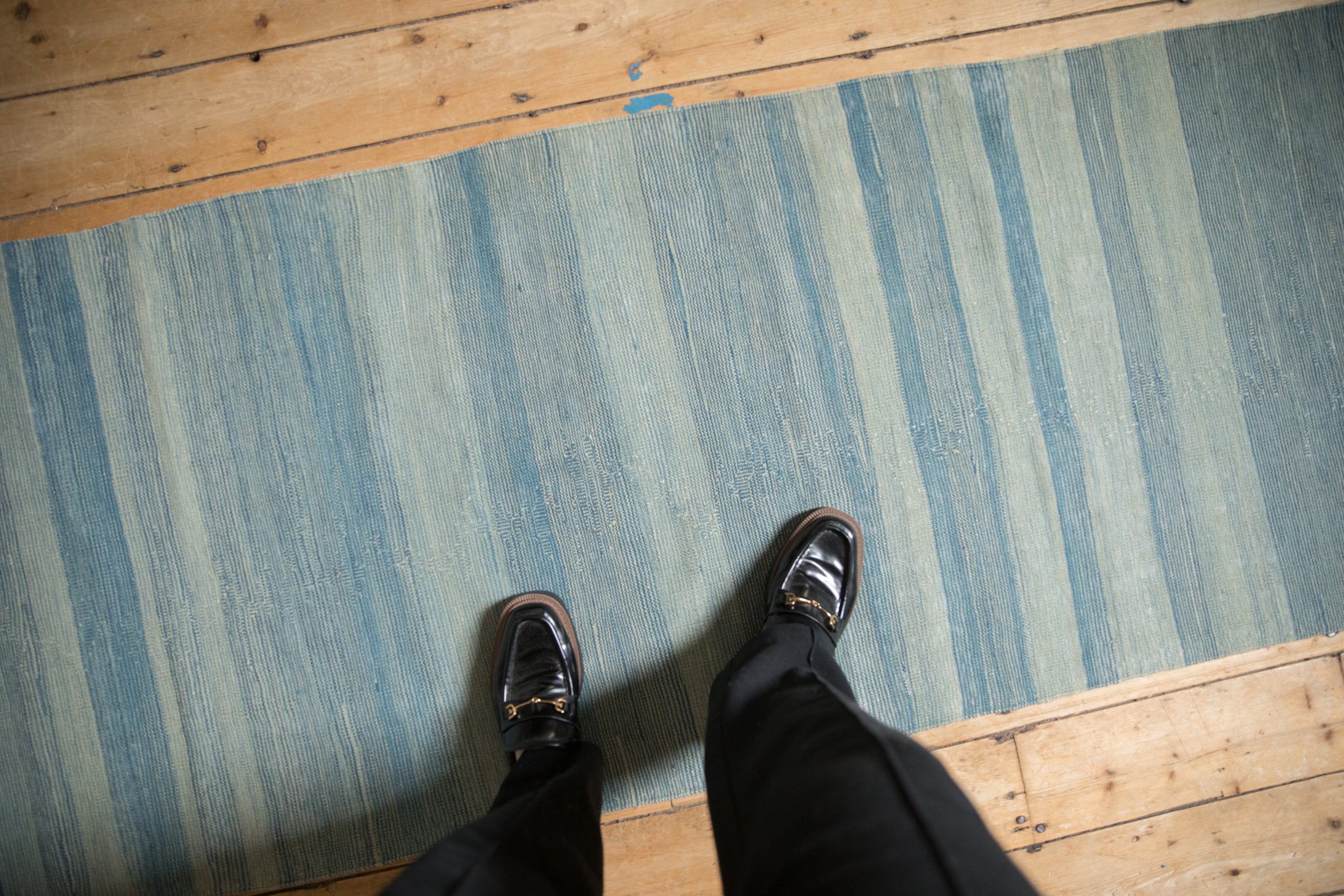 Pakistani Kilim runner displaying striated powder and denim blue abrashes, with shoes.
