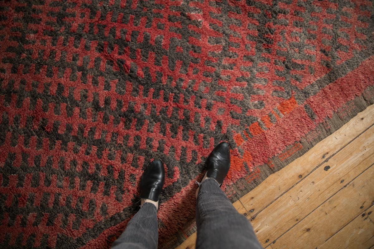Dense pile of Moroccan carpet showing abstract cross-hatched pomegranate red and charcoal design.