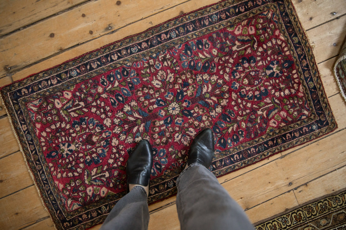 Hand-knotted Sarouk runner, cherry red field with dense floral sprays and triple navy border.