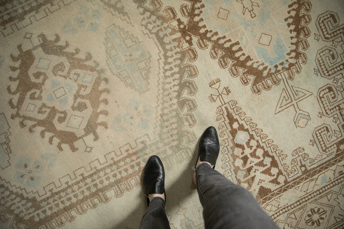Distressed Veece carpet texture showcasing ivory, coffee brown, and pale blue scrolled hook and latch motifs.