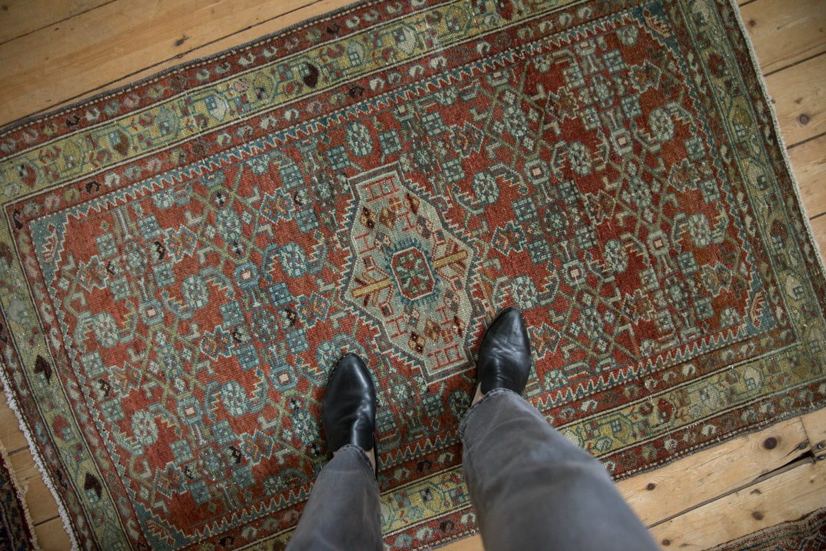 Distressed Mehraban rug section showing chestnut rust Herati pattern and slate blue borders.