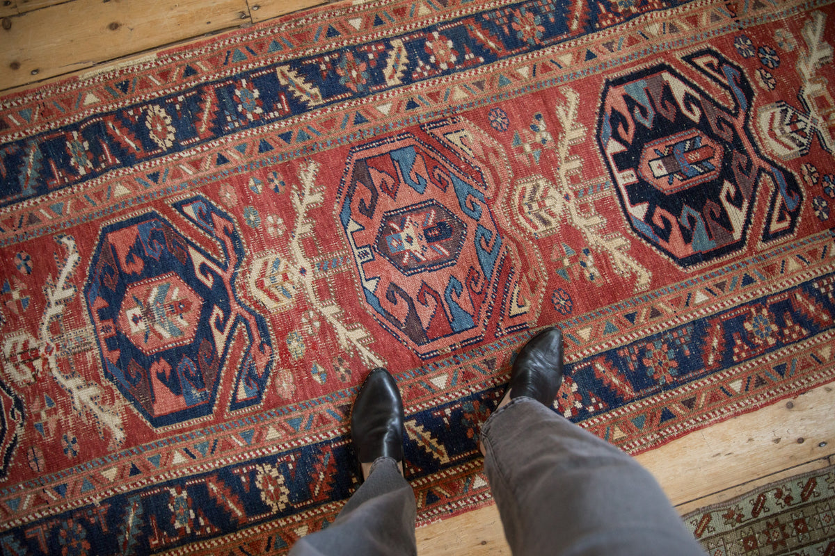 Antique Northwest Persian runner with cherry red field, sapphire blue pomegranate medallions, and plant motifs.