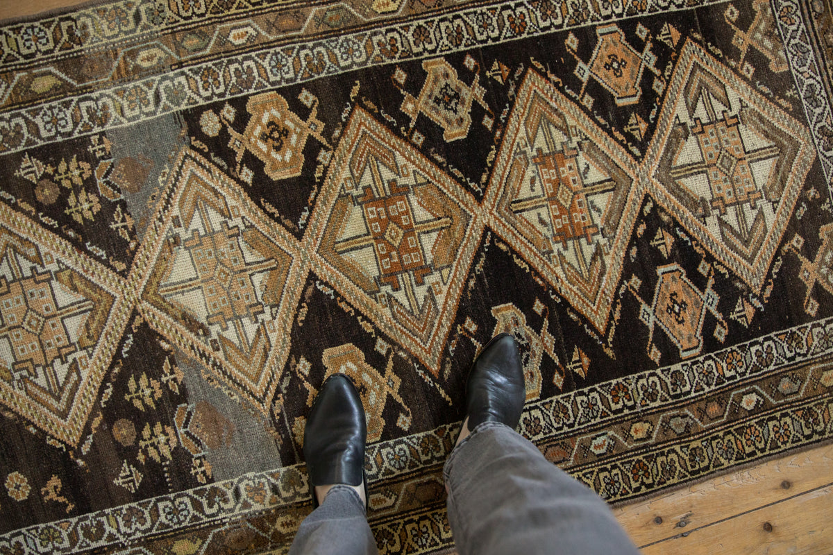 Distressed vintage Hamadan runner featuring geometric diamond medallions in beige and dark earth tones.
