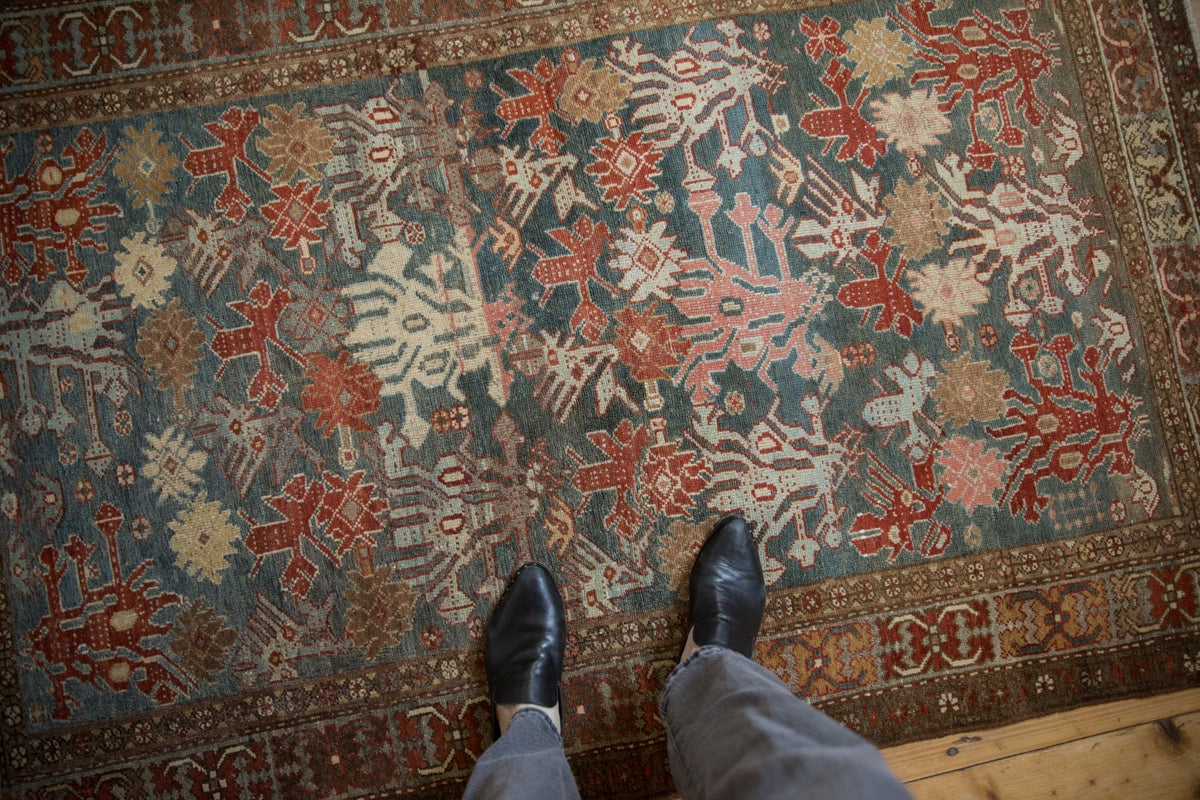 Distressed Hamadan rug showing dusty teal floral motifs and a crab style border.