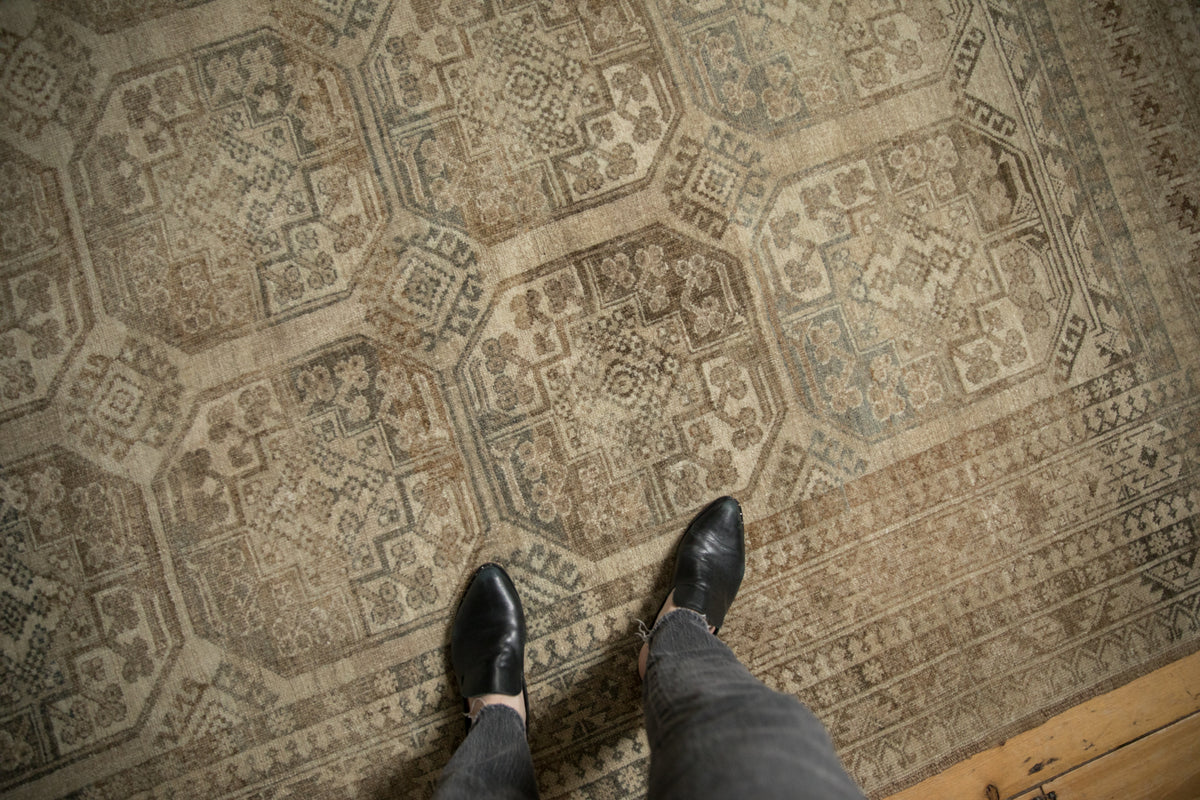 Distressed vintage Ersari carpet with faded octagonal guls, pawn motif, and abrash in sand and teal.