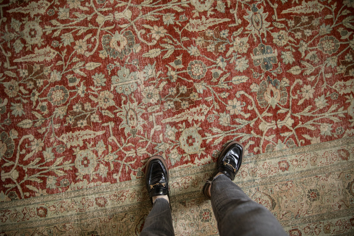Distressed Persian Tabriz: cherry red field, faded palmettes, vines, and worn main border.