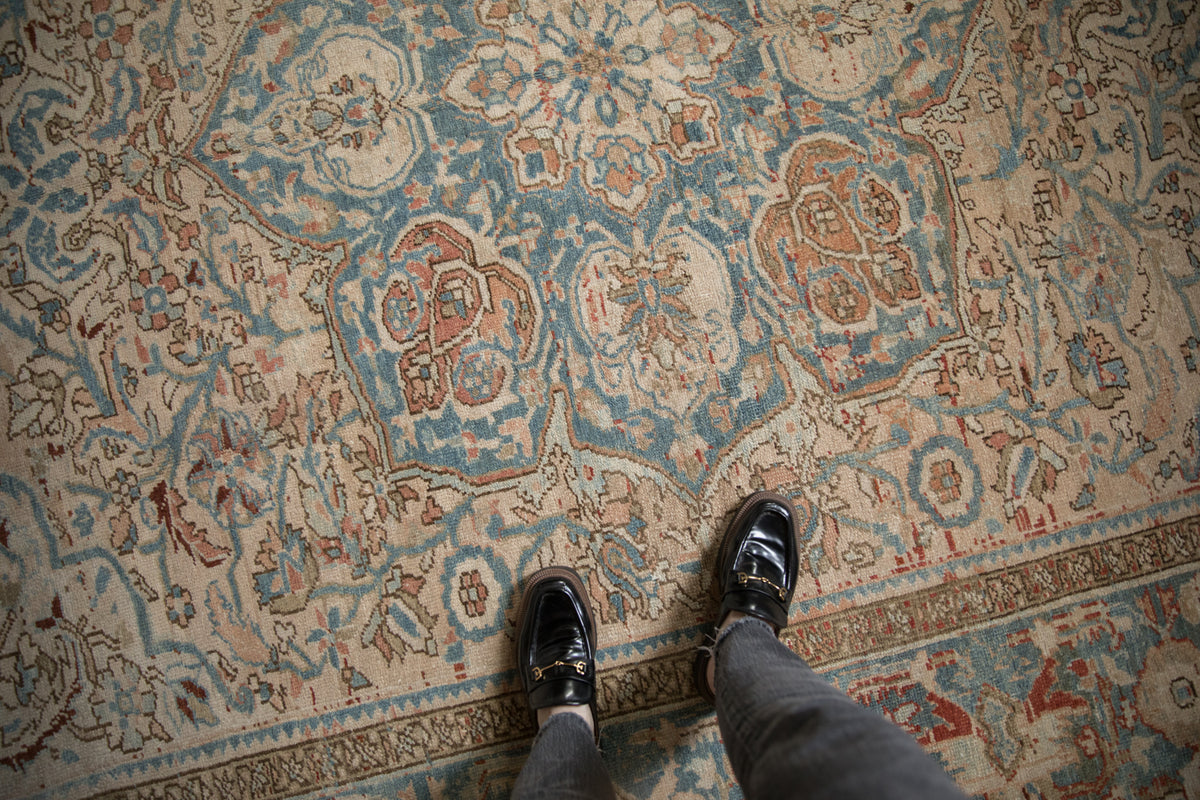 Distressed Persian Ahar rug with soft cream, dusty blue, and terracotta patterns, viewed from above.