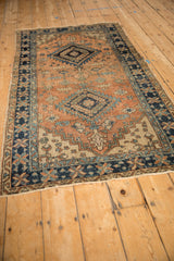 Vintage Northwest Persian rug corner: terracotta field with spandrel, navy pinwheel border.