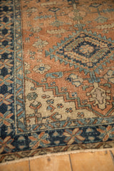 Heriz-area runner corner detail: terracotta, navy geometric leaves, meandering vine border, even wear.