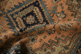 Folded pile of vintage Heriz-area rug showing terracotta, navy, and sky blue geometric leaves.