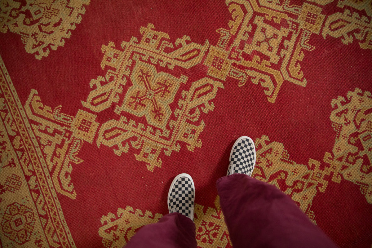 Intricate gold and seafoam geometric medallions on a vibrant cherry red vintage Oushak carpet.