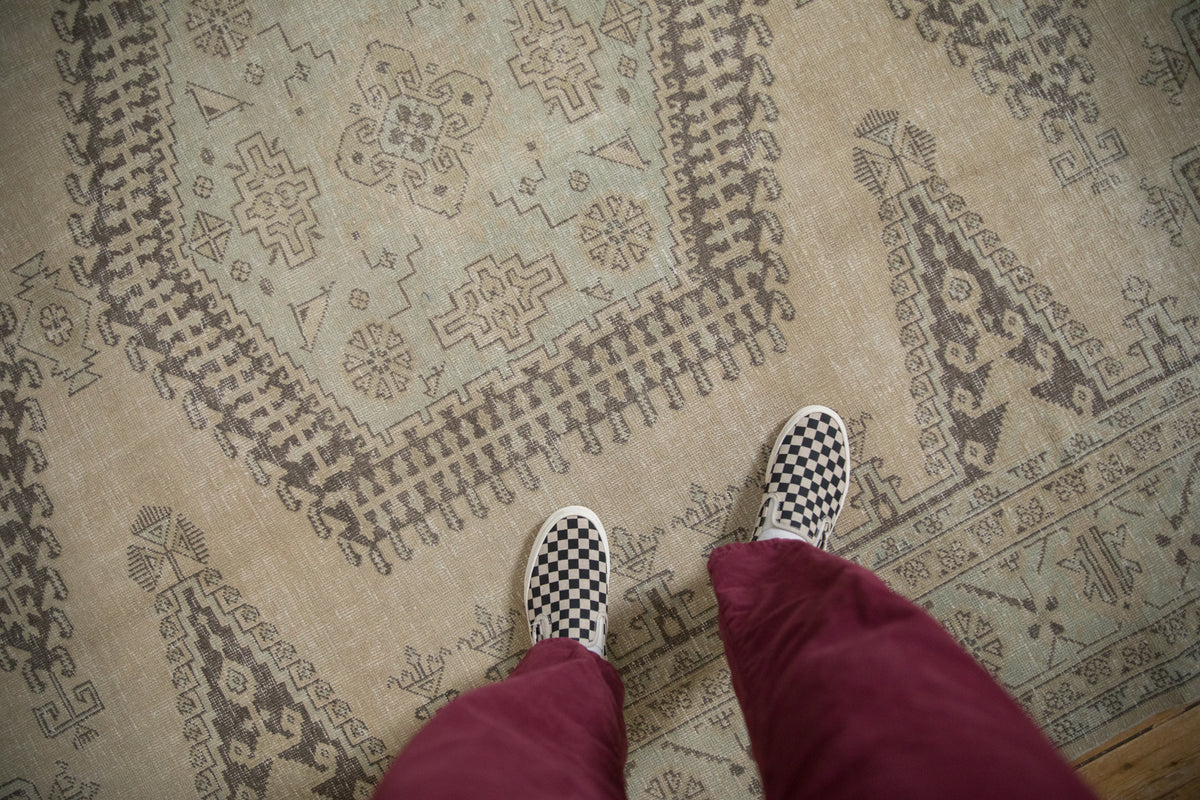 Distressed vintage Veece rug showing geometric hook and latch patterns in brown, cream, seafoam green.