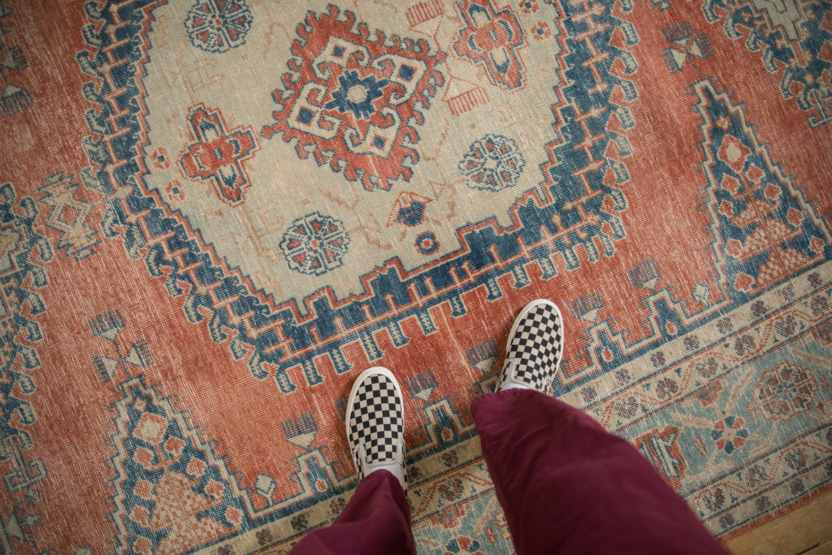 Worn texture and soft, faded melon red, dusty blue geometric pattern on a vintage Veece rug.