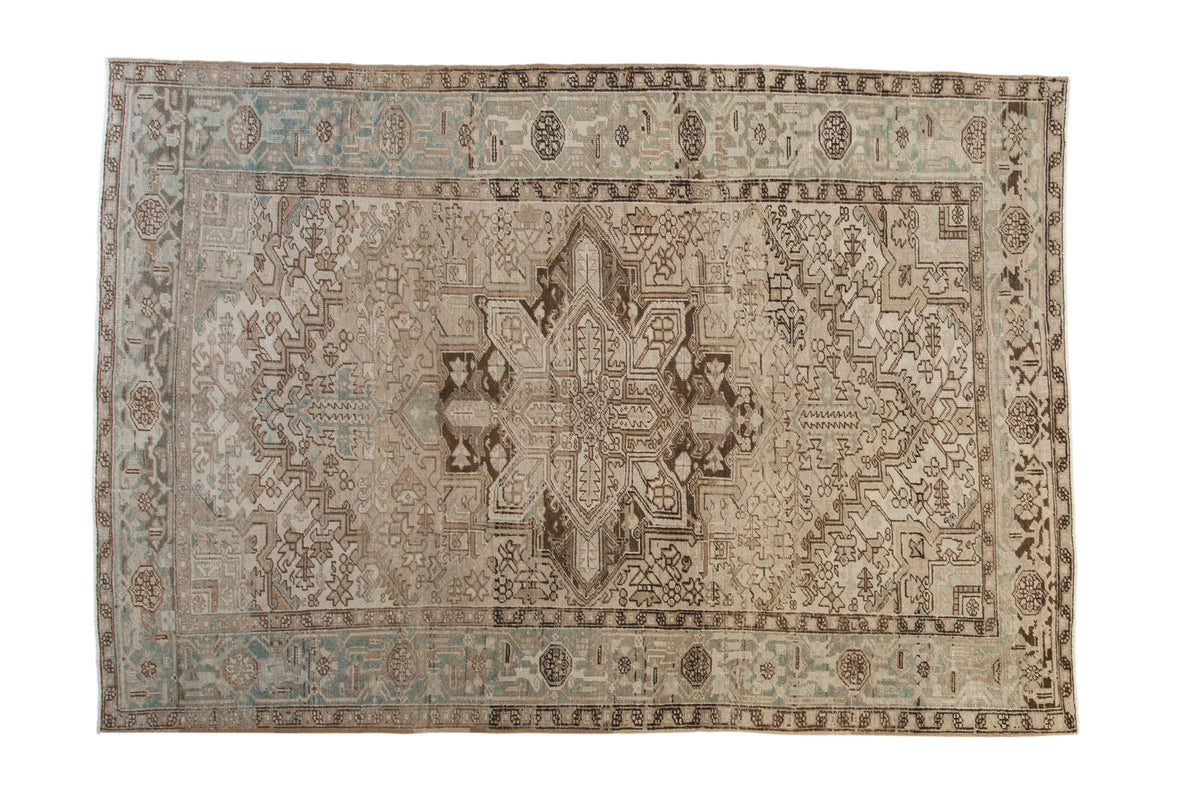 Distressed vintage Persian Heriz carpet, geometric starburst medallion, muted neutrals and faded teal.