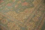 Corner of a Soumac carpet showing its Serapi-inspired border in pale gold and terracotta.