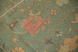 Hand-woven texture of a Soumac carpet with terracotta blossoms on a dark seafoam green field.