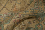 A soft fold in the Indian carpet displays its muted gold, sage, and terracotta pattern.