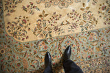Rococo-style floral vinery on the vintage carpet's ivory field and its pale blue border.