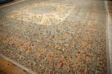 Angled view of a vintage carpet's corner showing detailed floral borders in pale blue, rose, and ivory.