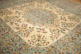 Close view of a vintage carpet's ornate Rococo border between the ivory and blue floral fields.