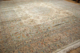 Intricate floral borders in pale blue and rose frame the ivory field of a vintage Kerman design carpet.