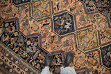 Textured pile of vintage Persian Ardebil carpet with peach and navy animal motifs.
