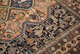 Navy and peach stylized animal and bird motifs on a vintage Ardebil carpet.