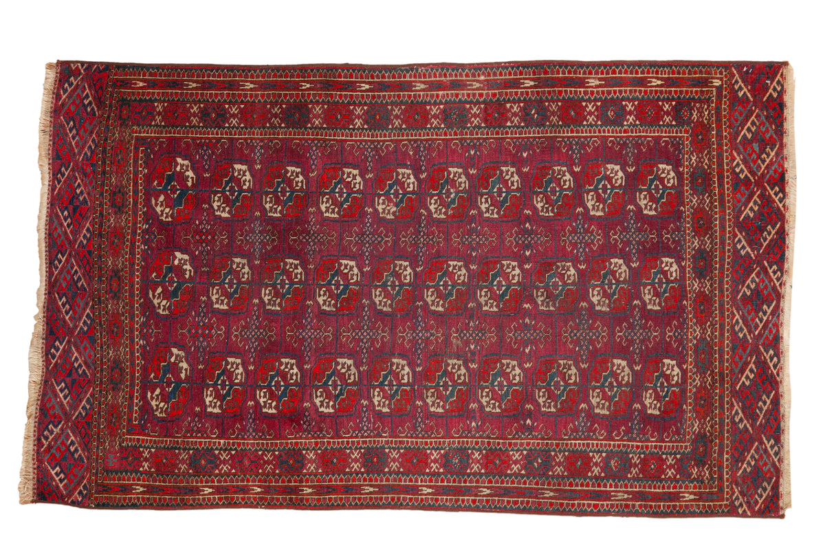 Vintage Tekke rug with repeating geometric gul motifs in burgundy wine red and dusty navy blue.