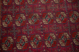 Close view of a vintage Tekke rug's finely knotted pile with geometric motifs in navy and beige.