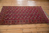 Angled view of a vintage Tekke rug in burgundy with repeating columns of gul motifs.