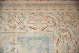 Time-softened floral arabesques in mauve and powder blue on this vintage carpet's corner border.