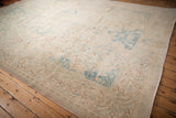 Low angle view of the vintage rug's distressed texture in faded ivory and powder blue.