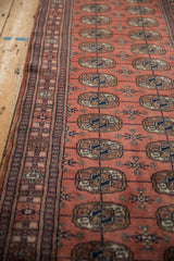 Lustrous, dark rose pile of a vintage Bokhara runner with detailed geometric gul medallions.
