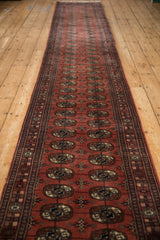 Angled view down the length of a fine Bokhara runner with repeating medallions.