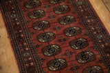 Detailed view of the tight weave and repeating gul medallions on a plush vintage Bokhara rug runner.